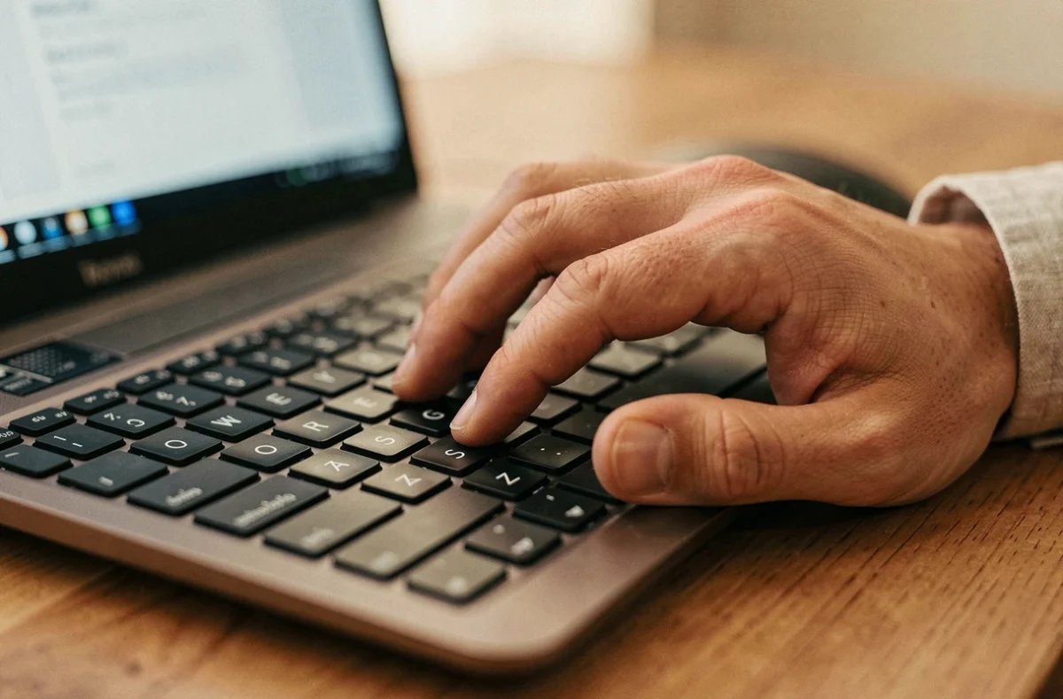 Gros plan sur la touche arobase d'un clavier AZERTY avec un doigt prêt à appuyer dessus